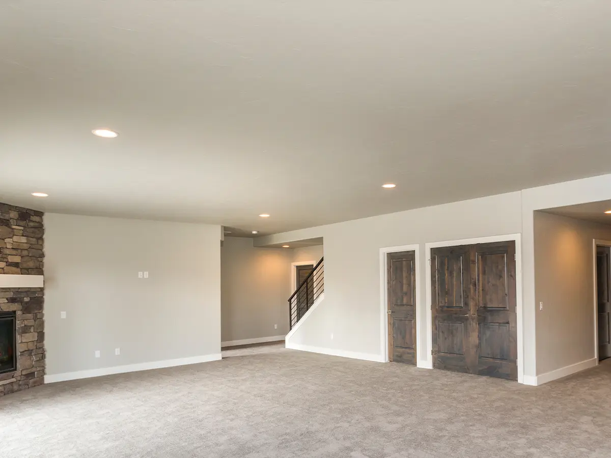 Basement with cream beige carpeting and white-gray walls, offering a spacious and inviting ambiance. Versatile space ready for customization, ideal for relaxation and entertainment. Expansive layout allows for personalized design and versatile use.