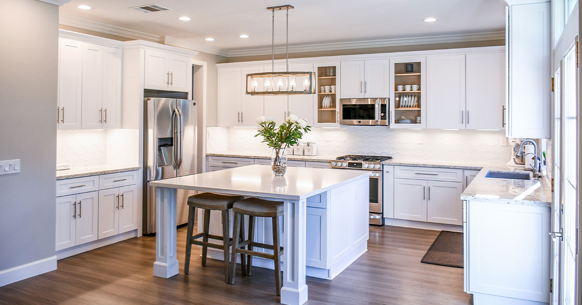 Modern kitchen with white cabinets, white quartz countertops, kitchen island and updated lighting.
