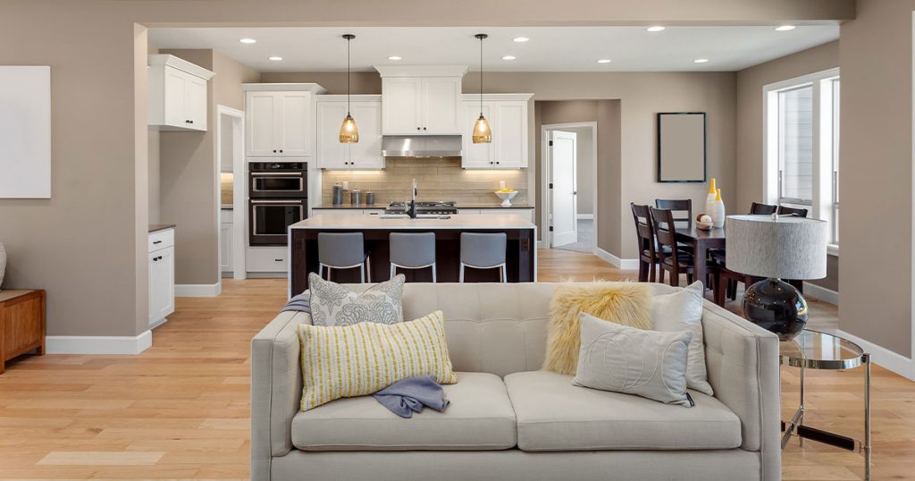 Transitional living space with light wood floors, white kitchen cabinets, and neutral-toned furniture throughout