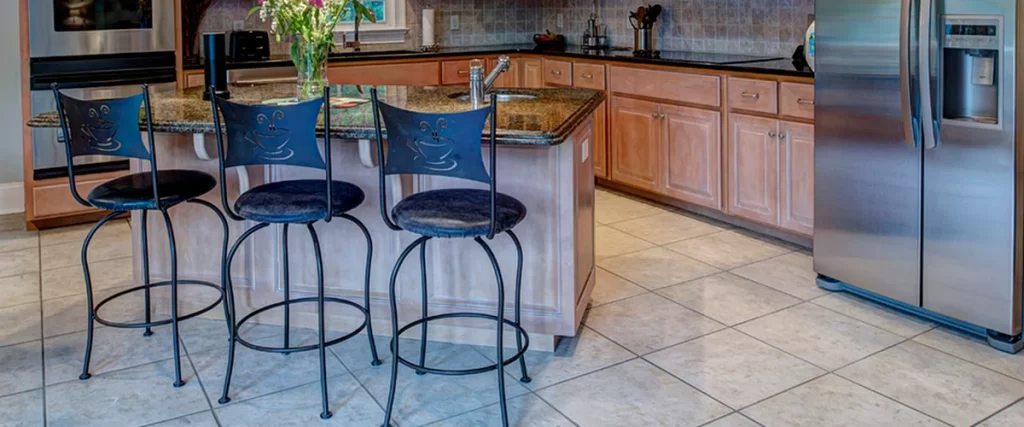 Traditional kitchen with tile flooring, wooden cabinets, stainless steel appliances, and a central island with bar seating