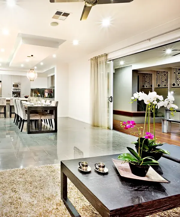 A sleek, modern dining area featuring polished grey floors and large sliding glass doors that open to an outdoor patio, highlighting a luxury home remodeling transformation.