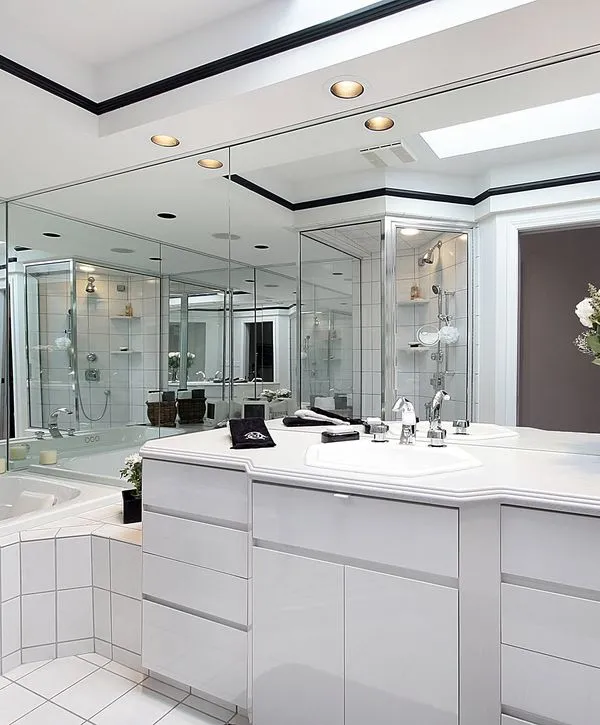 Spacious modern bathroom remodeling project featuring sleek white cabinets, extensive wall mirrors, black ceiling trim, and a glass-enclosed shower.