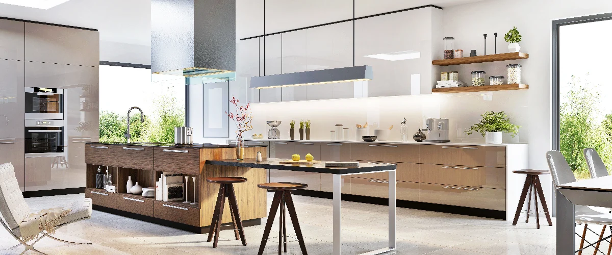 Contemporary kitchen design featuring glossy white upper cabinets, tan lower cabinets, a large wood-textured island with an extended eat-in table, and large windows overlooking green trees.